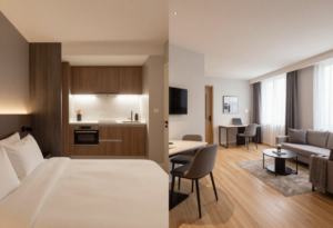 Modern studio corporate apartment with bed, kitchenette, workspace, and living area in a spacious open layout